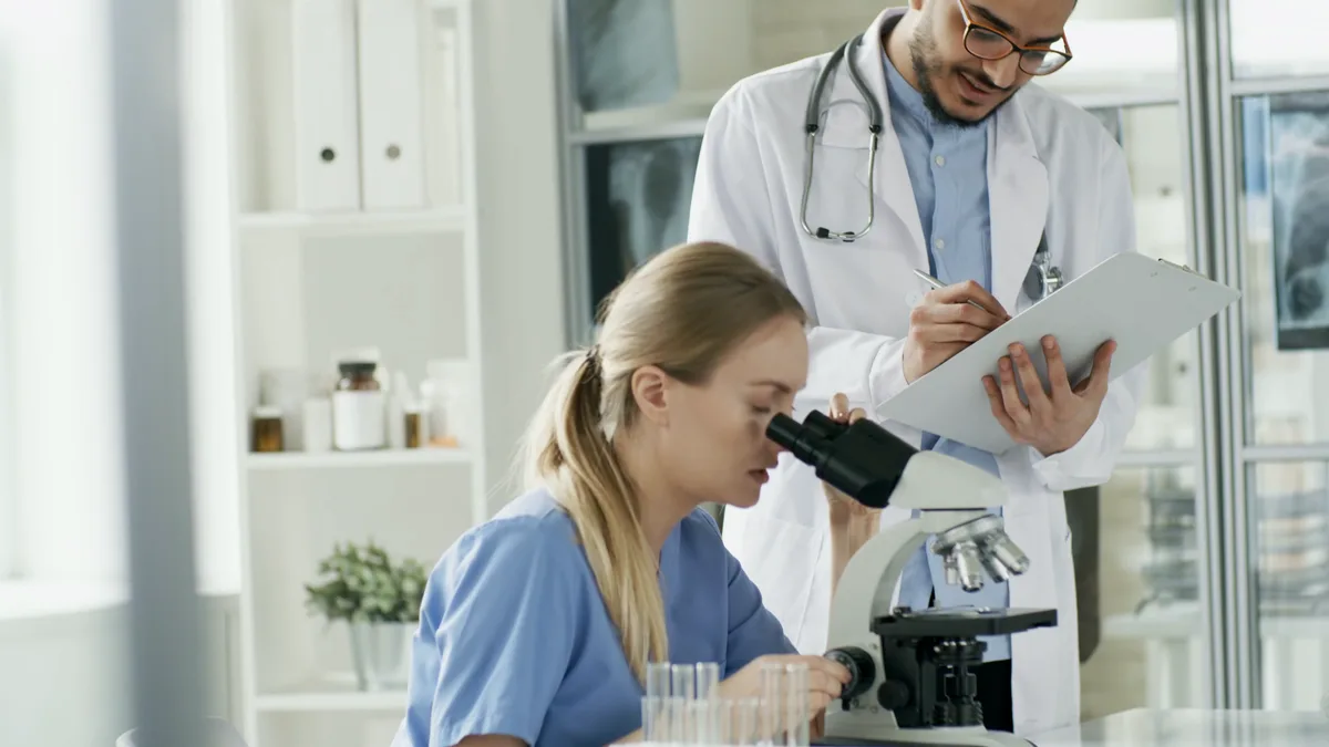 A Numou dietitian taking notes beside a colleague at a microscope
